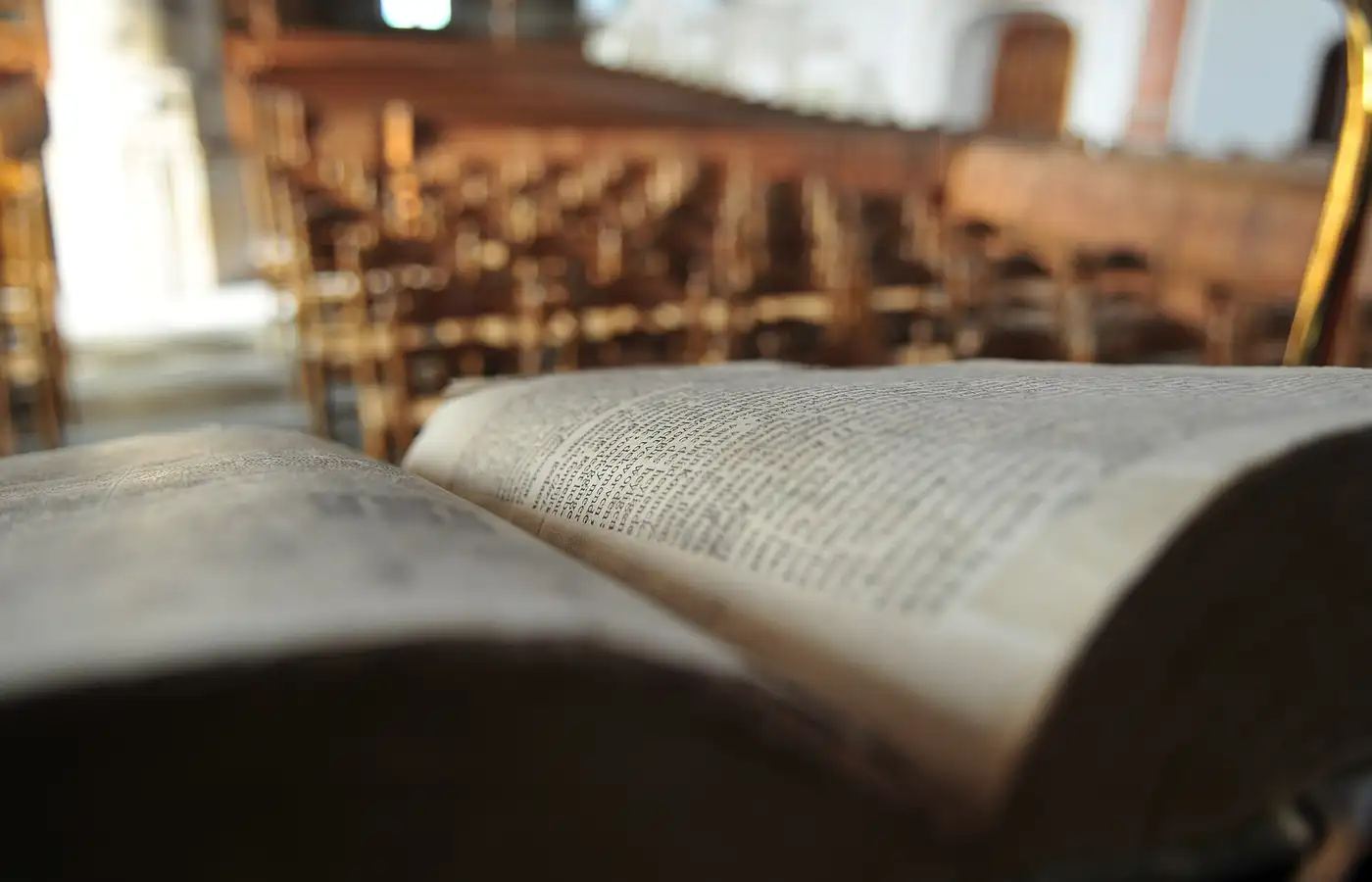 ’n Oop Statenbybel op ’n lessenaar, met die banke van ’n gereformeerde kerk daaragter.